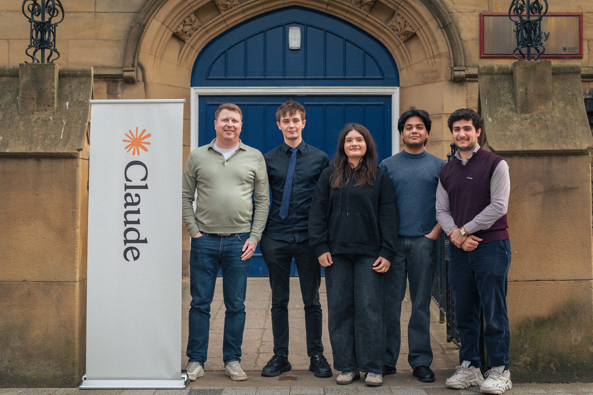 A team photographed in front of the Claude banner