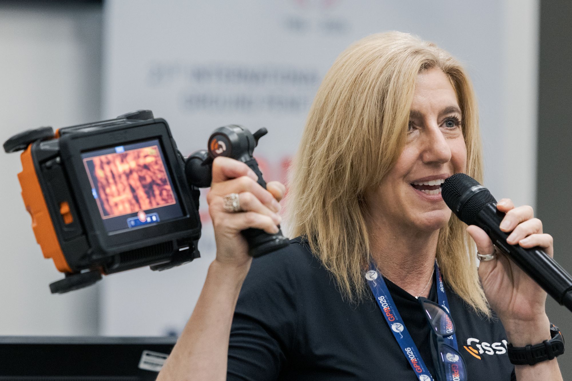 A presenter holding a handheld ground-penetrating-radar unit while speaking